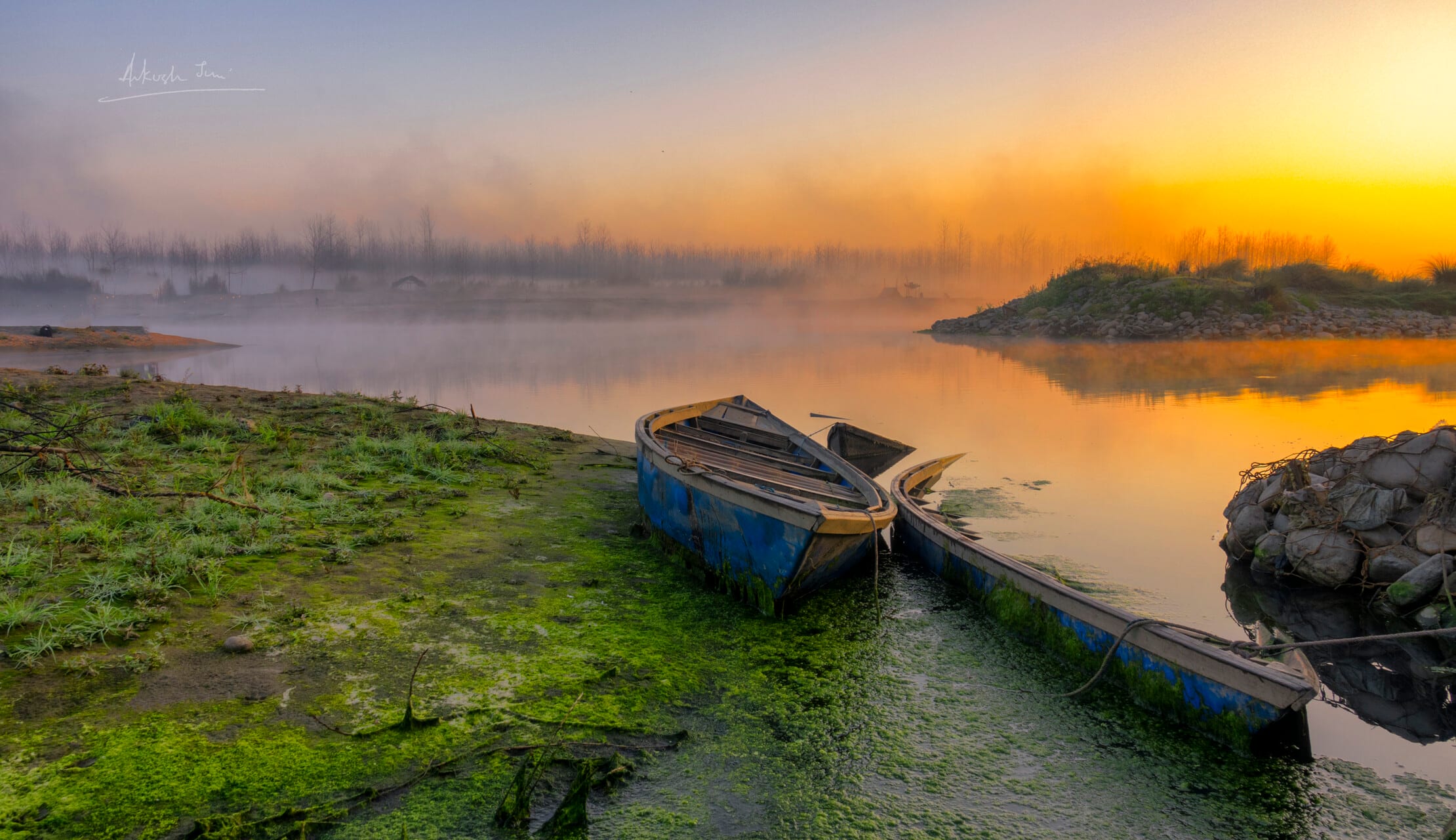 Wooden boats moored on the Satluj at sunrise, misty bank