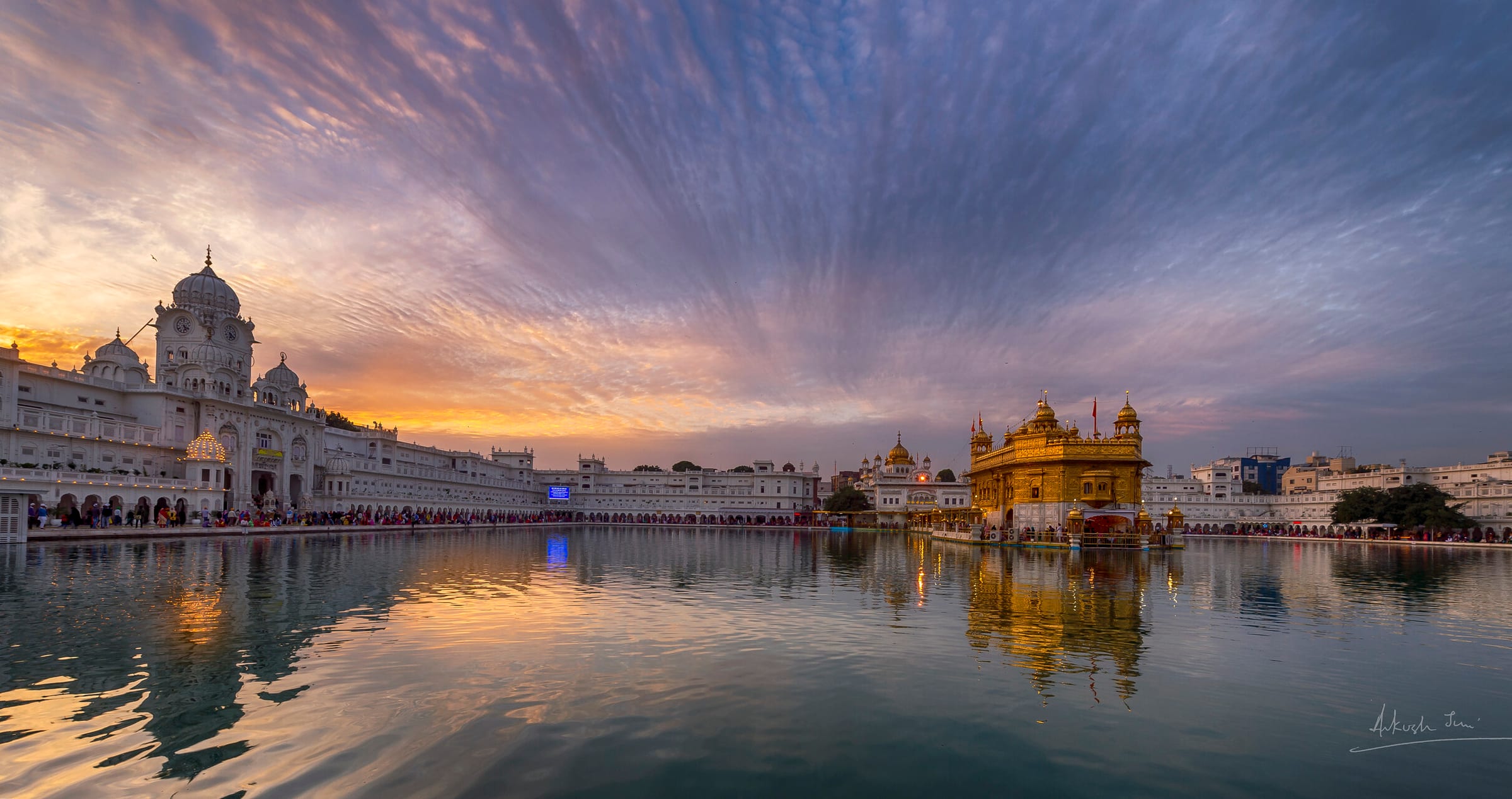 Harmandir Sahib and the clock tower reflected in the sarovar at sunset