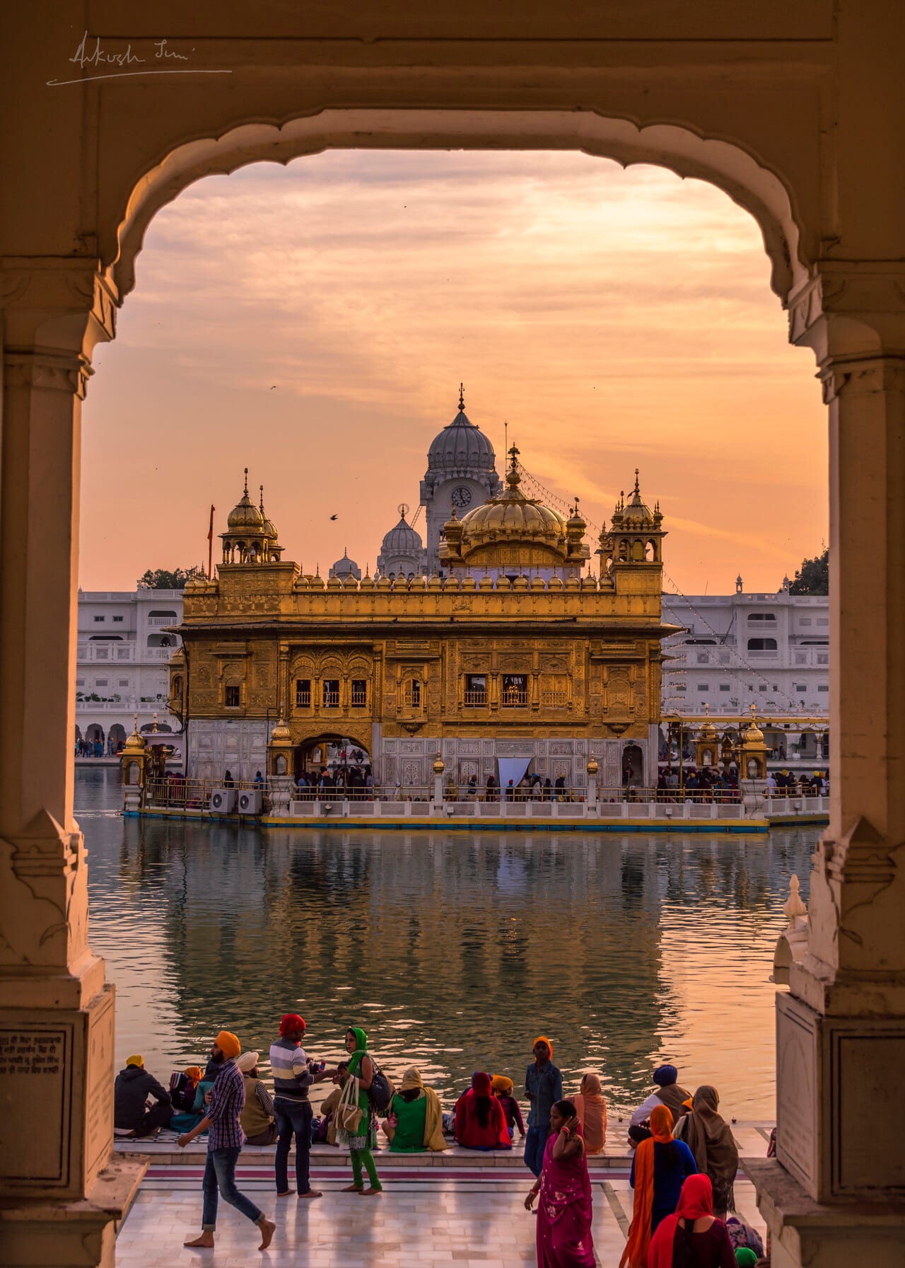 Pilgrims at the parikrama, Harmandir Sahib framed by an archway at sunset