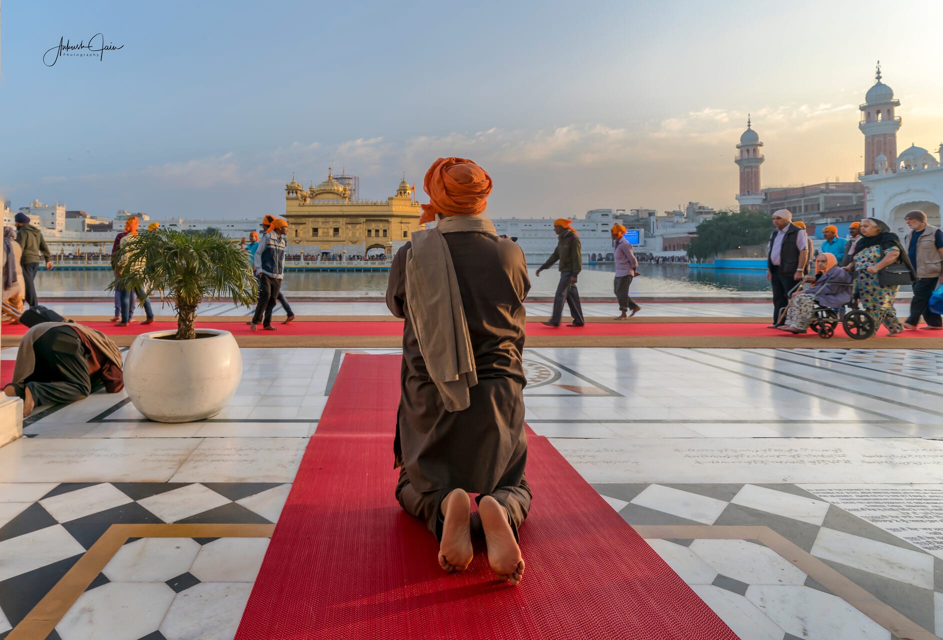 A devotee kneels in prayer on the parikrama as visitors pass