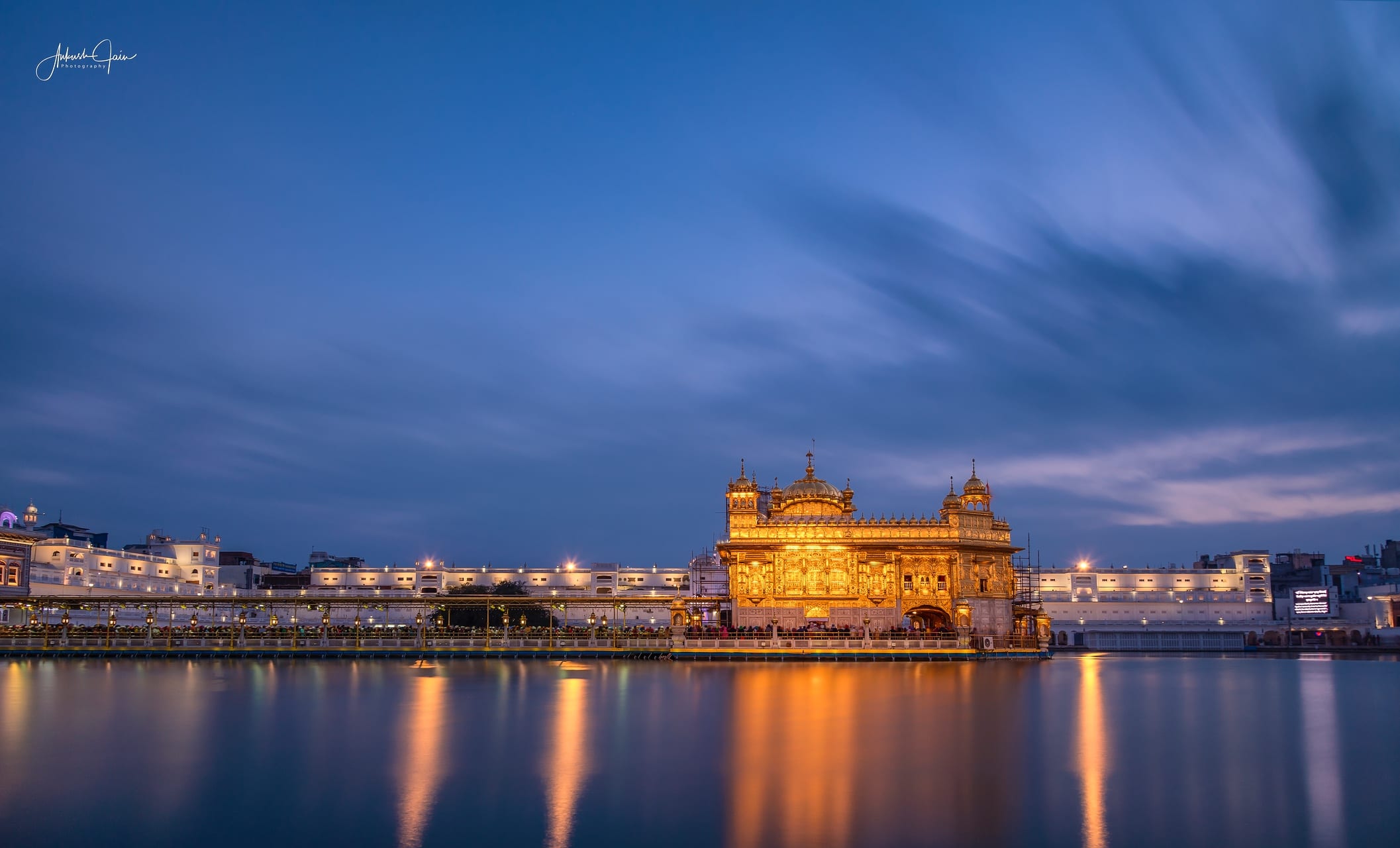 Long-exposure dusk view of the lit Harmandir Sahib reflected in still water
