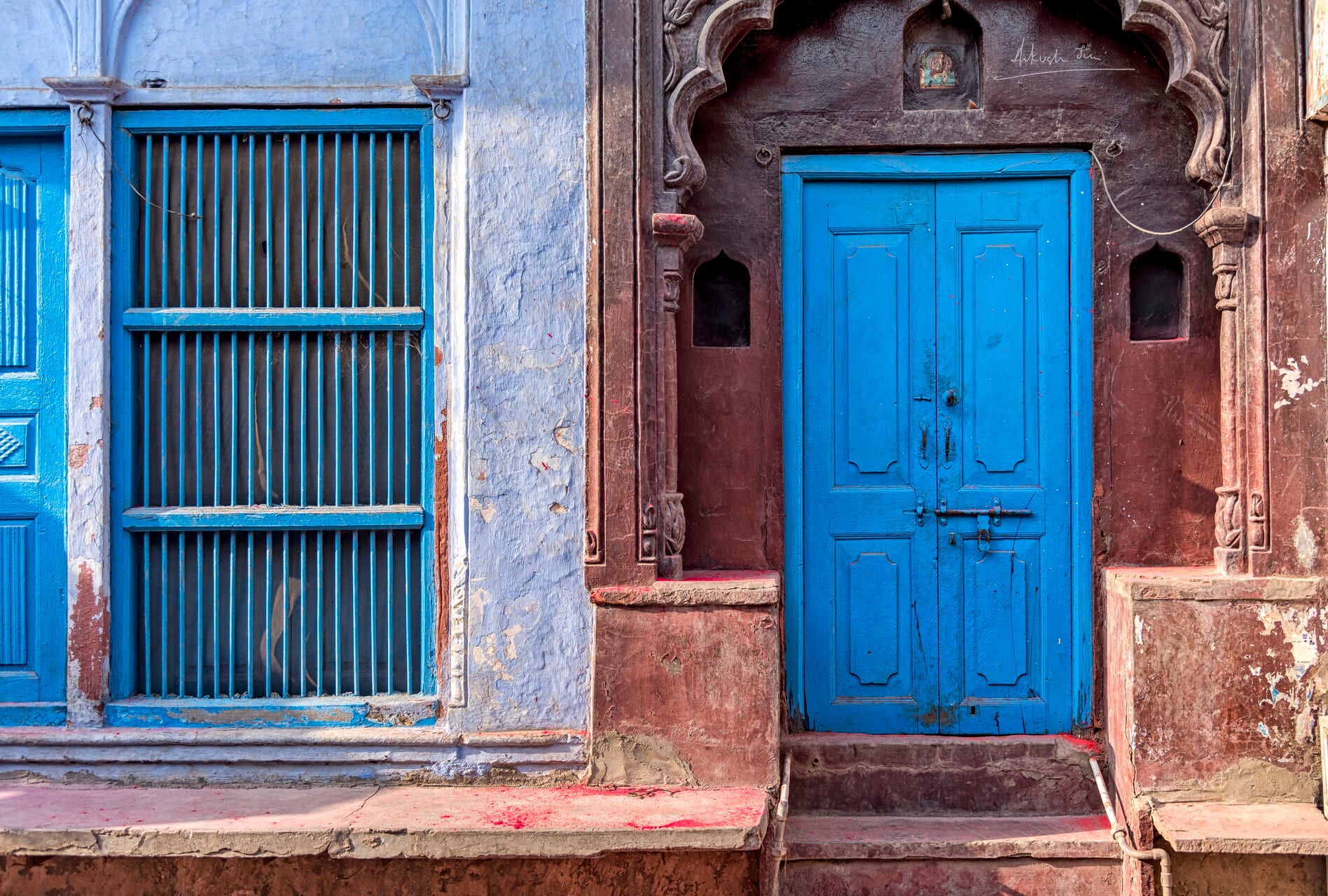Indigo blue door and barred window set into a pink-washed Vrindavan facade