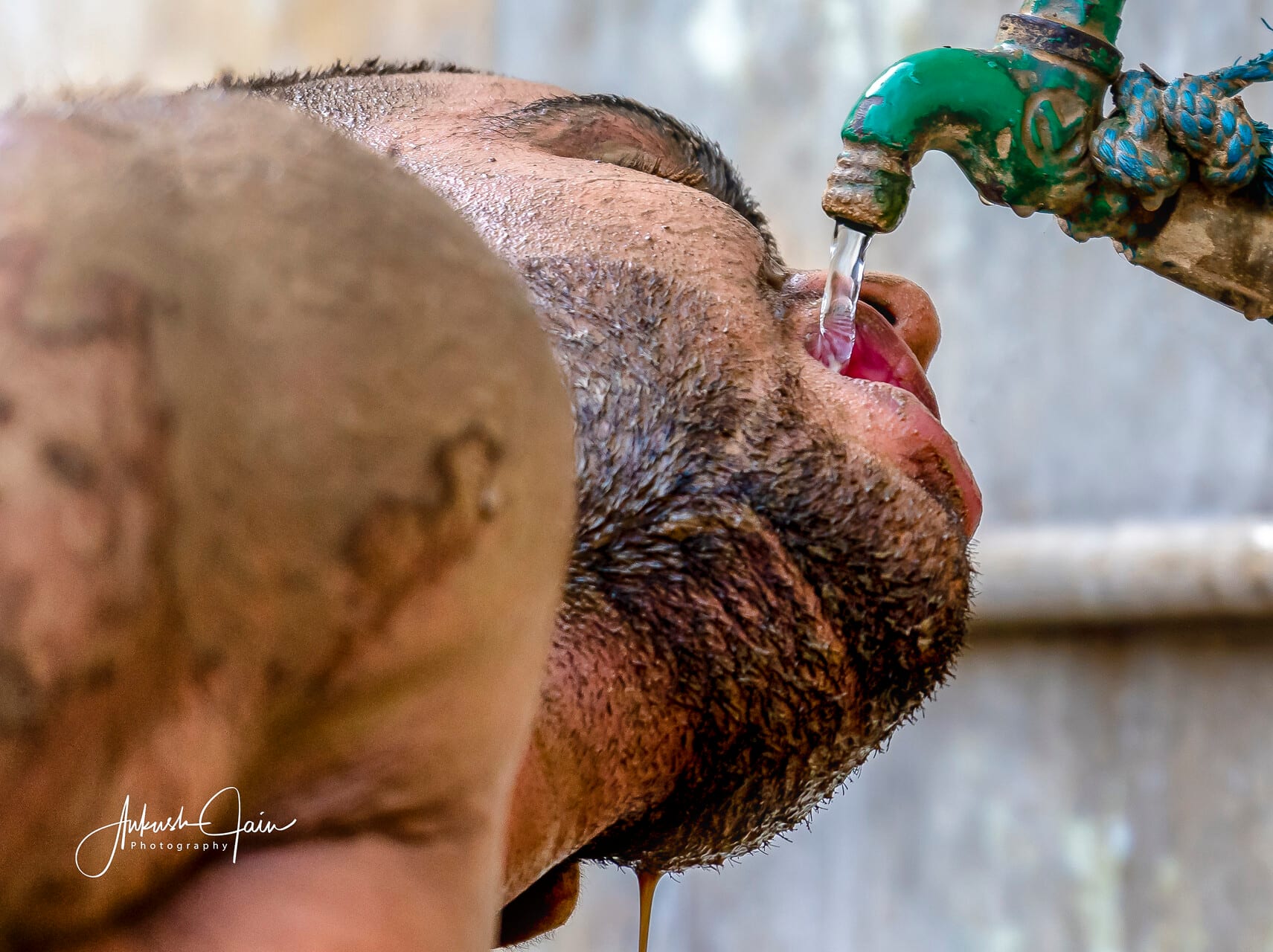 Young wrestler quenching his thirst at a street tap after a bout at Alamgir akhara