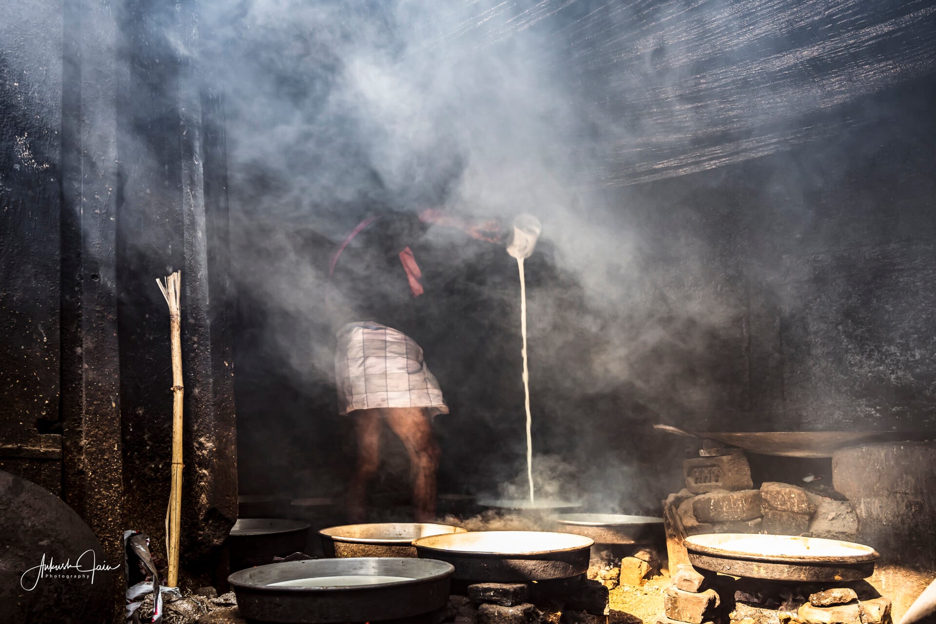 Worker stirring a steaming cauldron of milk for a street sweet in a Varanasi alley