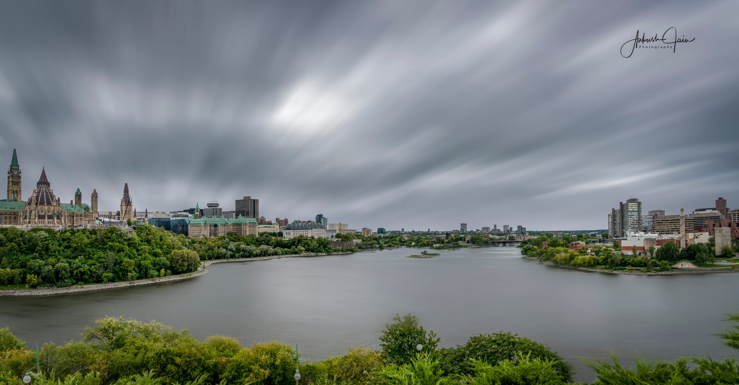 Long-exposure of the Ottawa skyline across the river, Parliament and the Peace Tower under streaked clouds