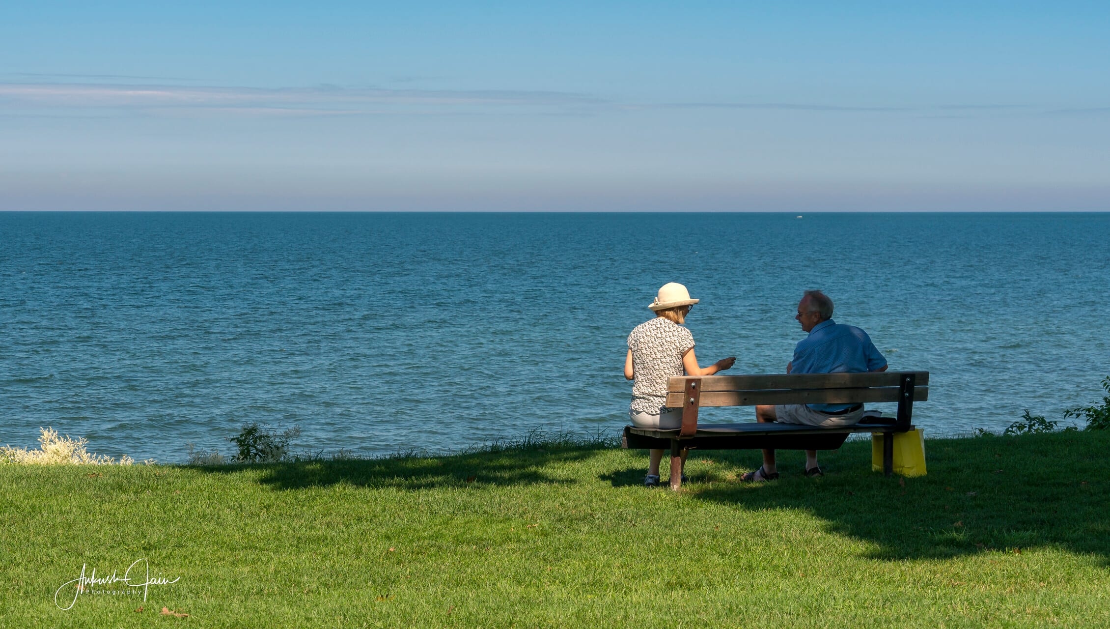 An older couple resting on a bench looking out over Lake Ontario at Niagara-on-the-Lake