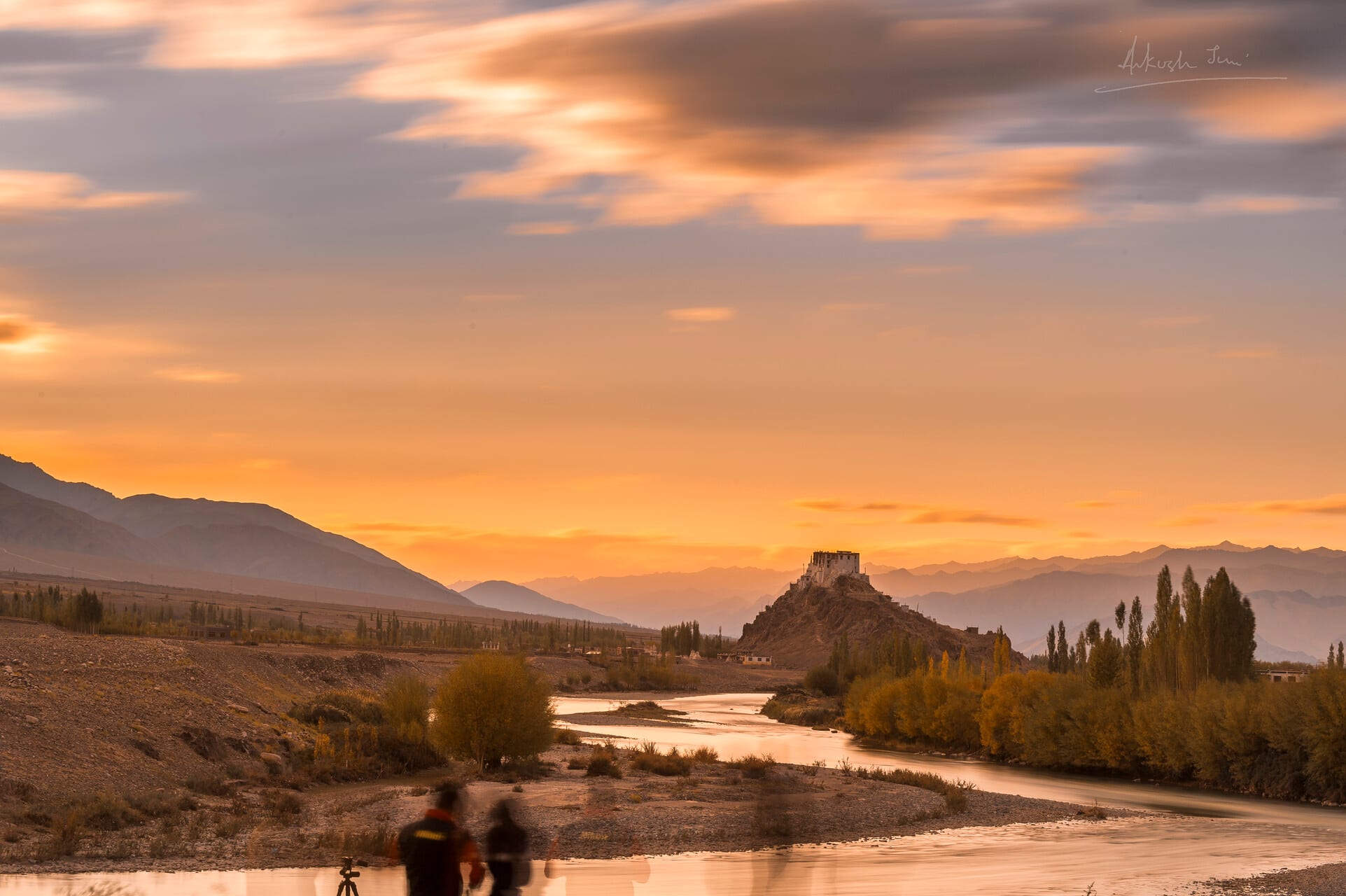 Stakna monastery silhouetted on its mound at sunset, the Indus winding past