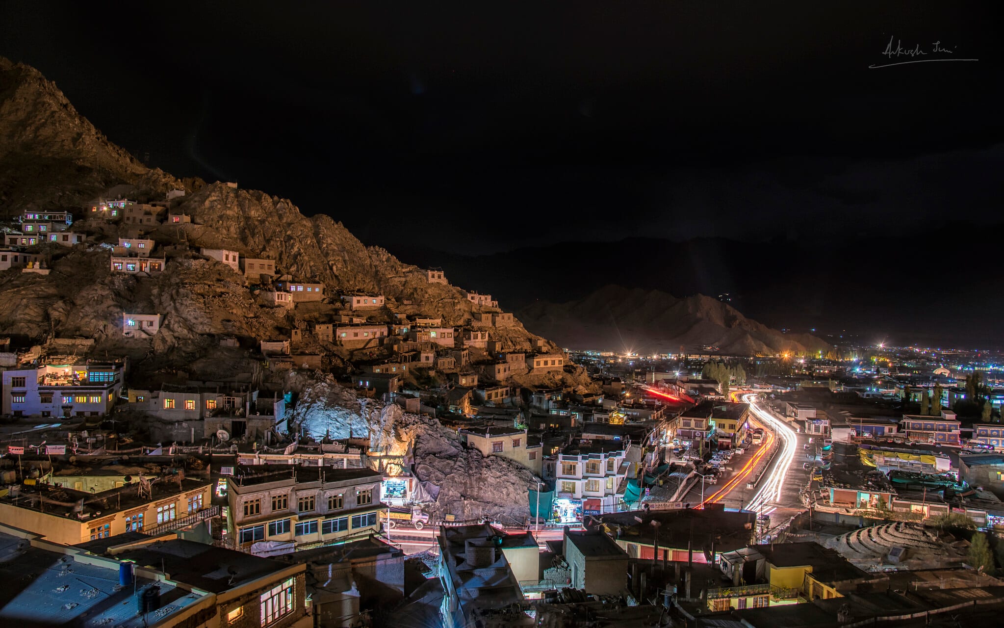 Night view of Leh with the palace above and light trails through the bazaar below