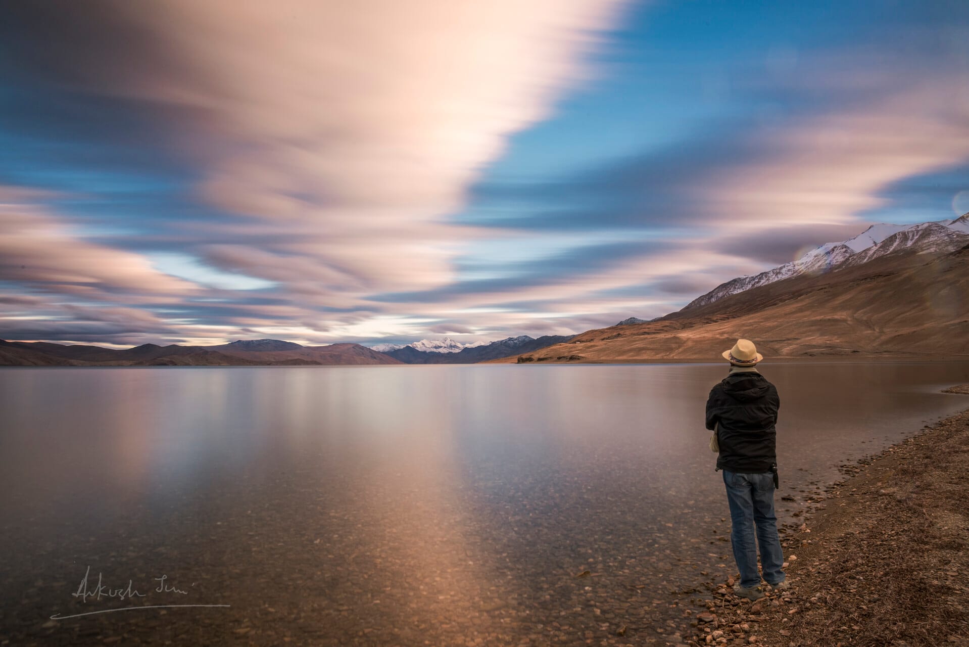 Self-portrait beside the still waters of Tso Moriri under streaked long-exposure clouds