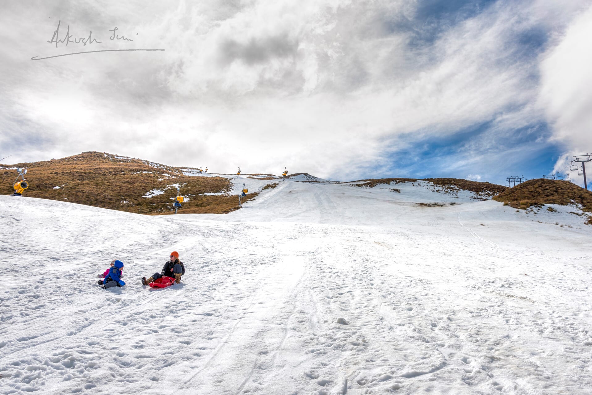 Family sledging down a snowy slope at Coronet Peak near Queenstown