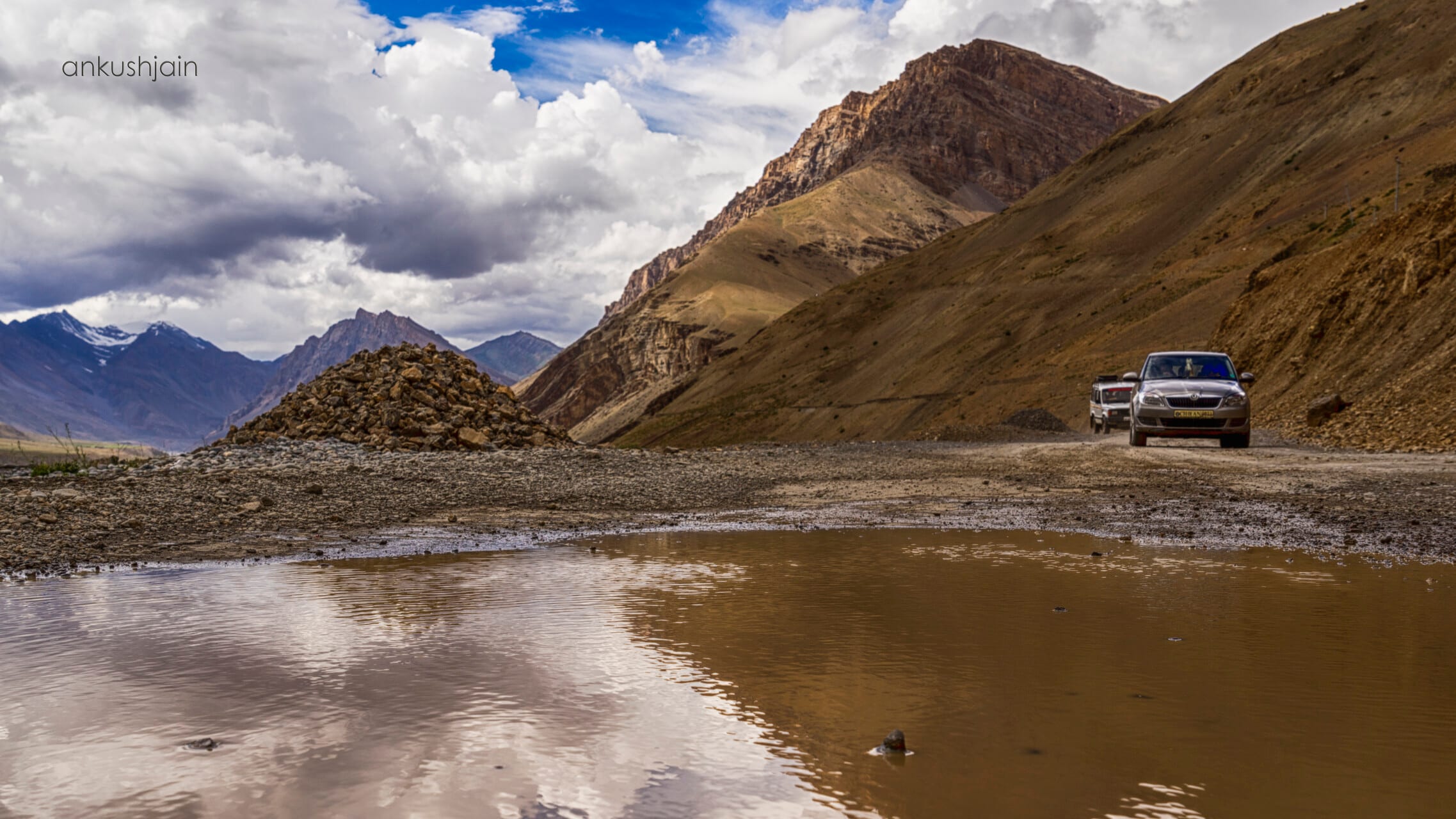 An empty dirt road winding through a barren high-altitude landscape