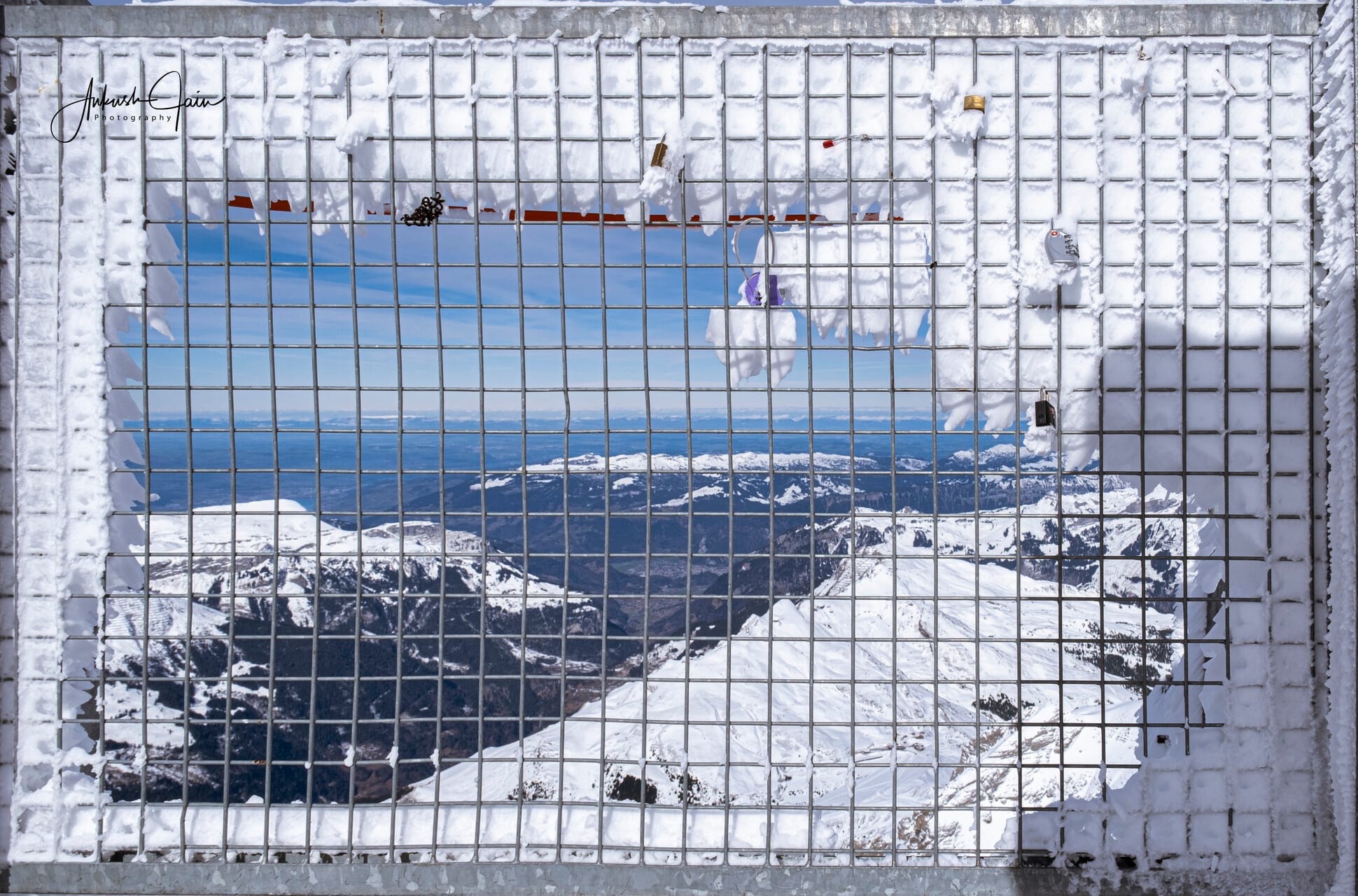 Looking straight down through an ice-encrusted observation grate at Jungfraujoch onto the snowy ridges far below