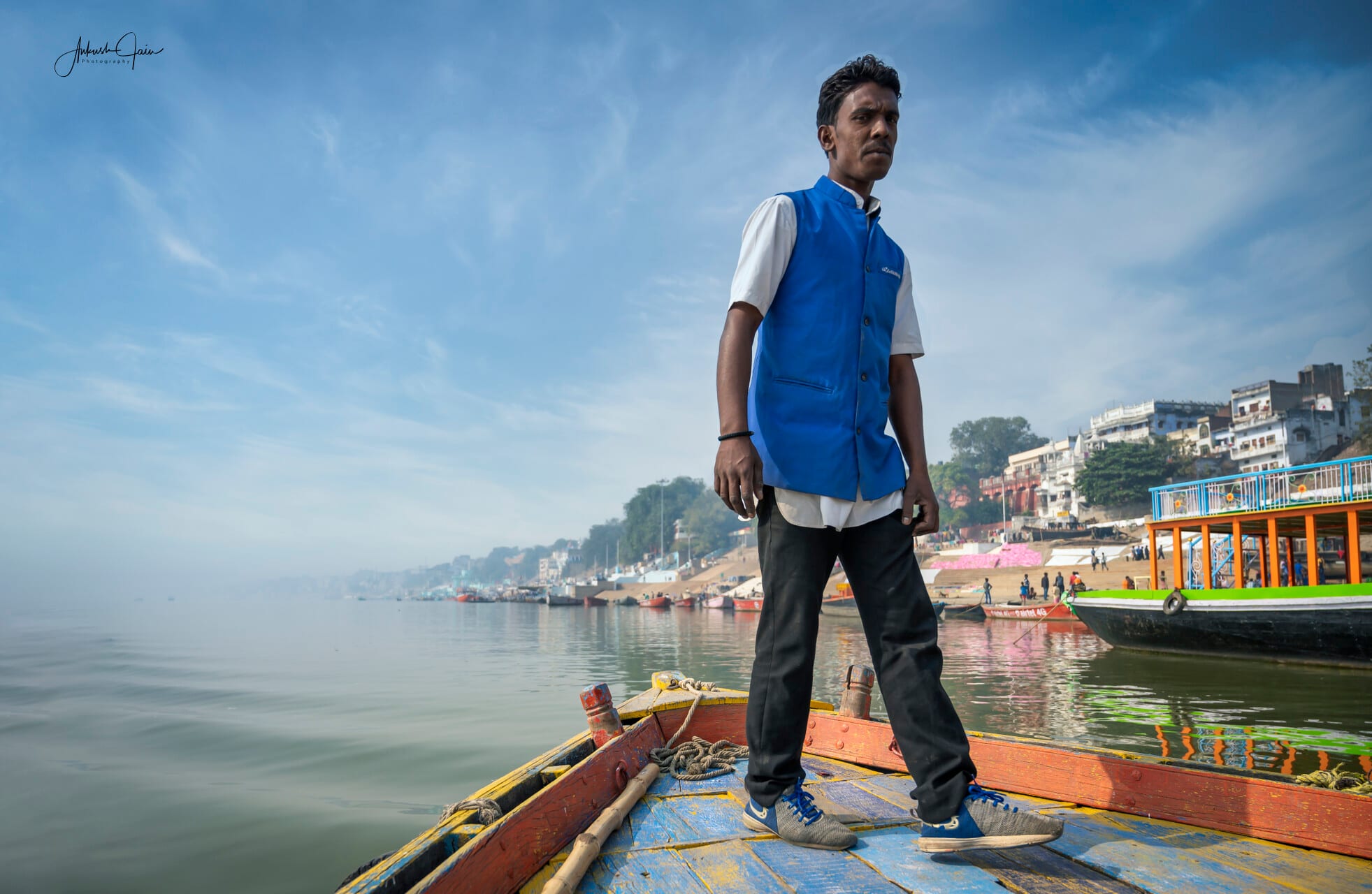 Young boatman standing on his prow, waiting to take guests on a Ganga cruise, Varanasi